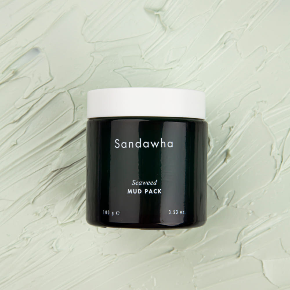 SANDAWHA Seaweed Mud Pack 100g, pot noir de la marque SandaWha sur fond crème texturé, vue produit