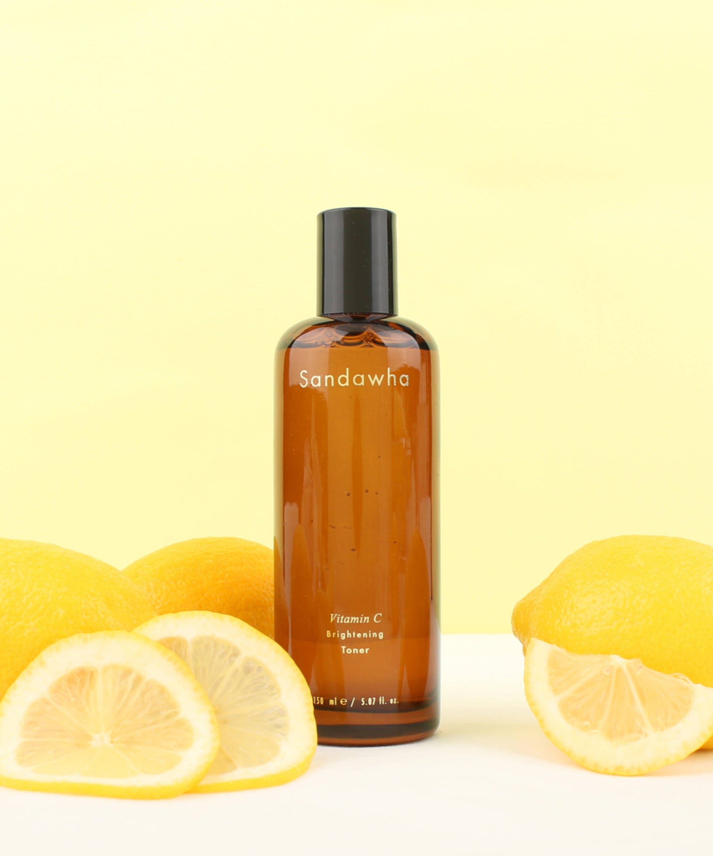 SANDAWHA Vitamin C Whitening Toner 150ml, bouteille avec citrons sur fond jaune en studio, marque Sandawha
