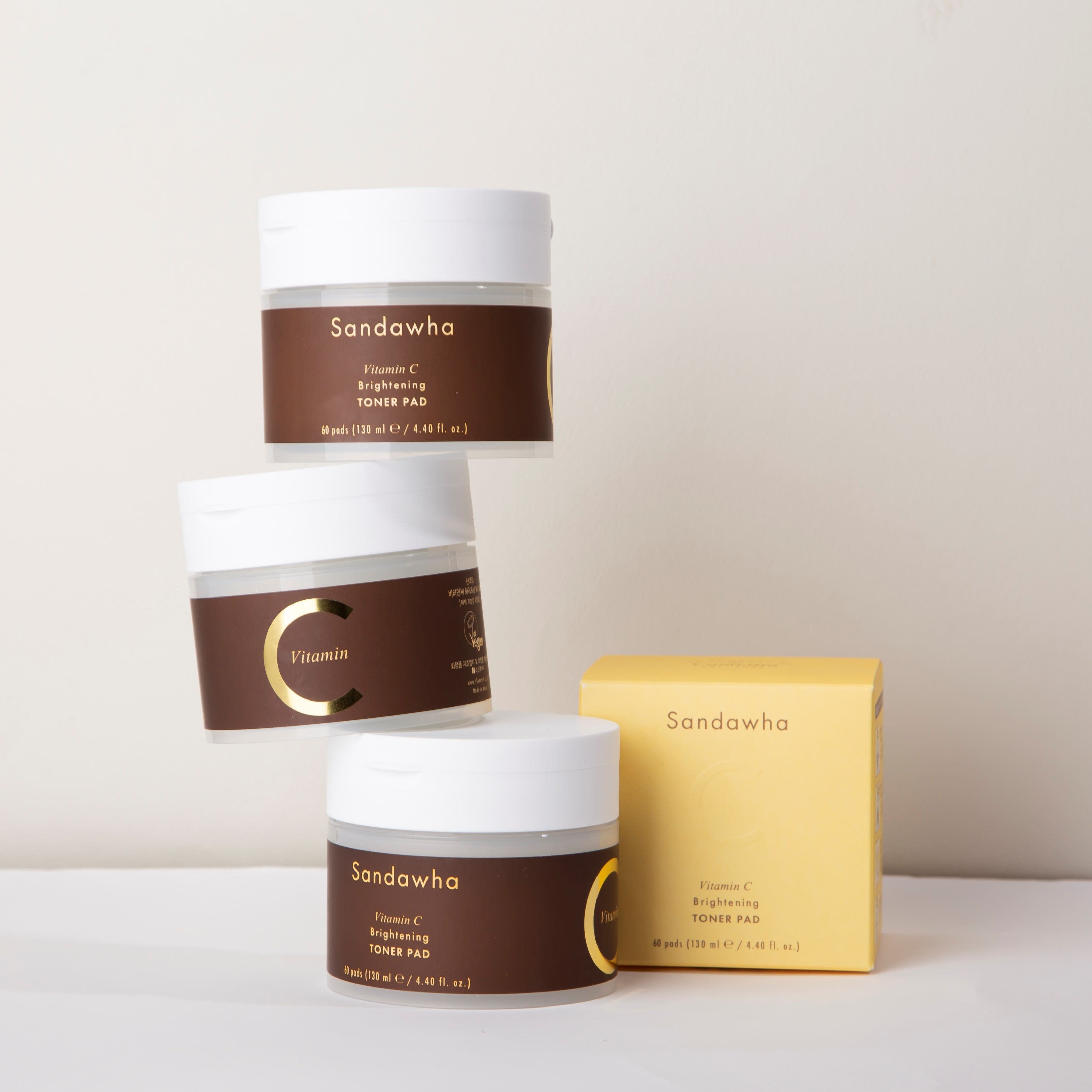 SANDAWHA Vitamin C Whitening Toner pad 60 Sheets, marque Sandawha, pots et boîte sur fond clair, packaging cosmétique.