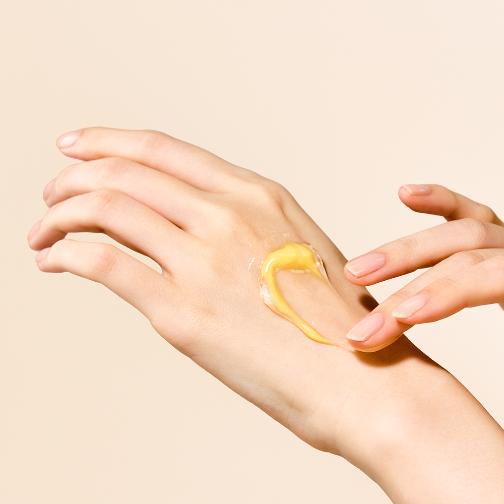 SEOUL 1988  Niacin Yuja Capsule Cream 50ml : mains appliquant une crème jaune sur peau, ambiance cosmétique minimaliste.