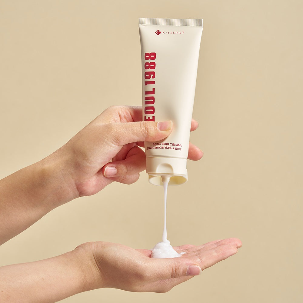SEOUL 1988 Snail 93 Cream 100ml, tube de crème snail noir/rouge S-ecret, tenue en mains sur fond beige.