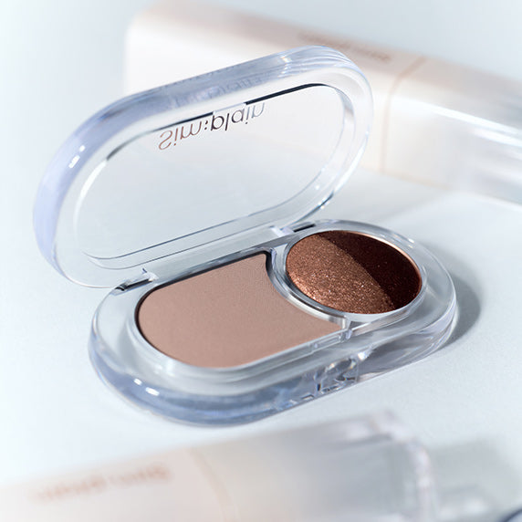 SIM;PLAIN Gleam On Eyes, fard irisé dans son boîtier ouvert sur fond blanc, gros plan maquillage.
