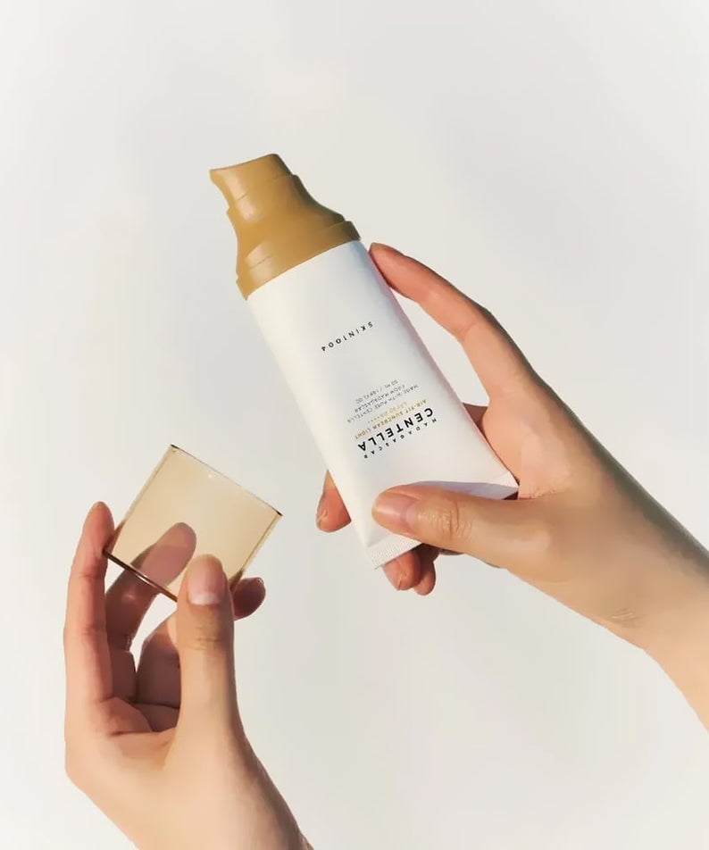 SKIN1004 Madagascar Centella Air-fit Sunscreen Light 50ml, main tenant un flacon crème solaire sur fond clair, vue produit.