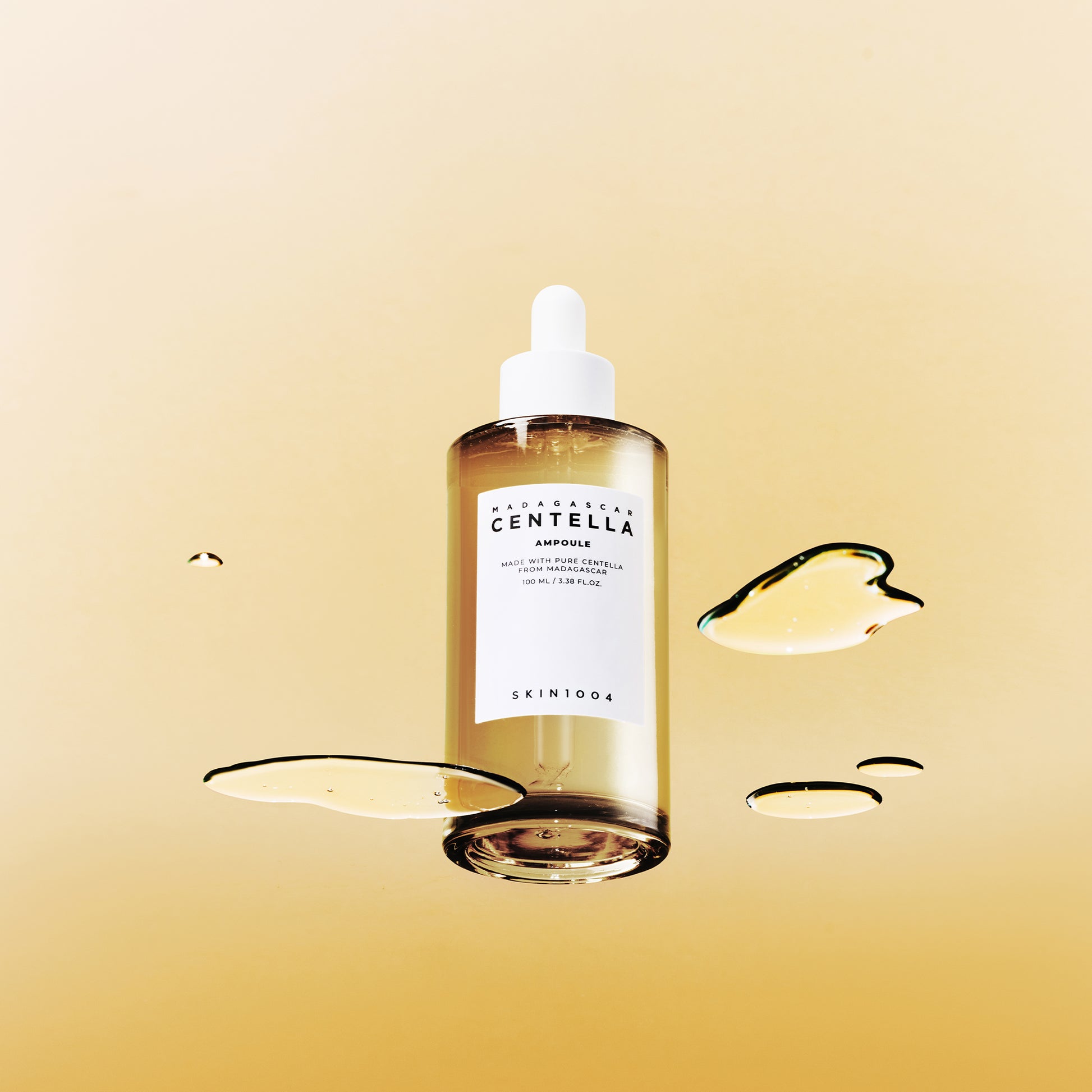SKIN1004 Madagascar Centella Ampoule 100ml de SKIN1004 sur fond beige, gouttes de sérum illustrées, contexte visuel beauté.
