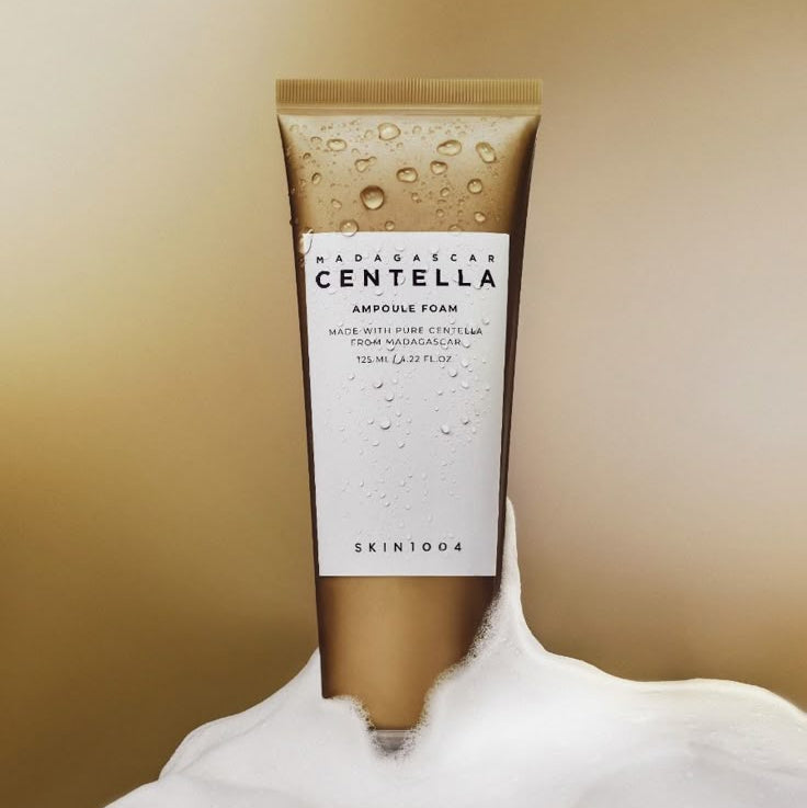 SKIN1004 Madagascar Centella Ampoule Foam 125ml, SKIN1004 en flacon sur fond beige, texture mousse et gouttes d’eau.