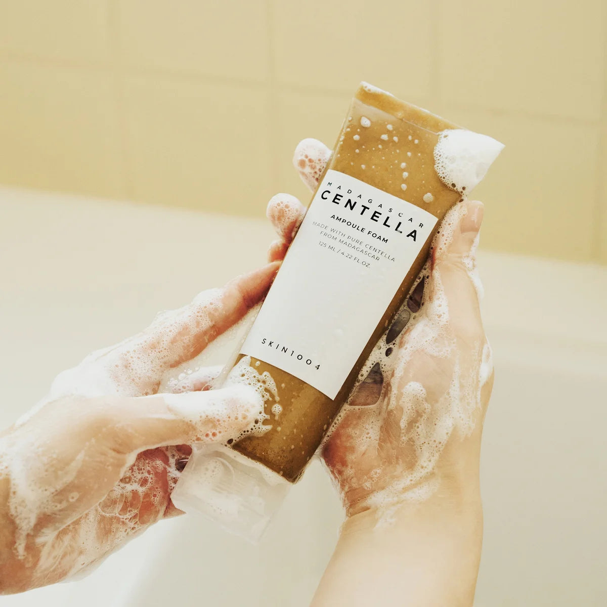 SKIN1004 Madagascar Centella Ampoule Foam 125ml : mousse sur mains, flacon SKIN1004 en contexte salle de bain, marque centella.