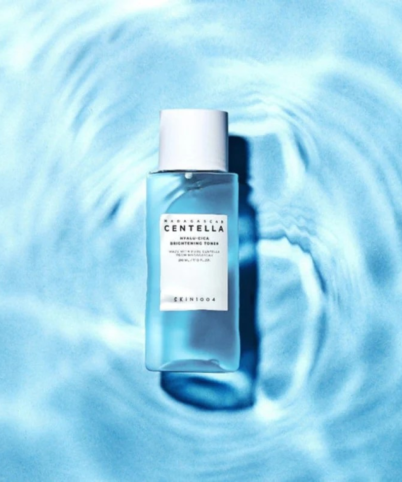 SKIN1004 Madagascar Centella Hyalu-Cica Radiance Toner 210ml de SKIN1004, flacon bleu sur fond bleu textures d’eau.