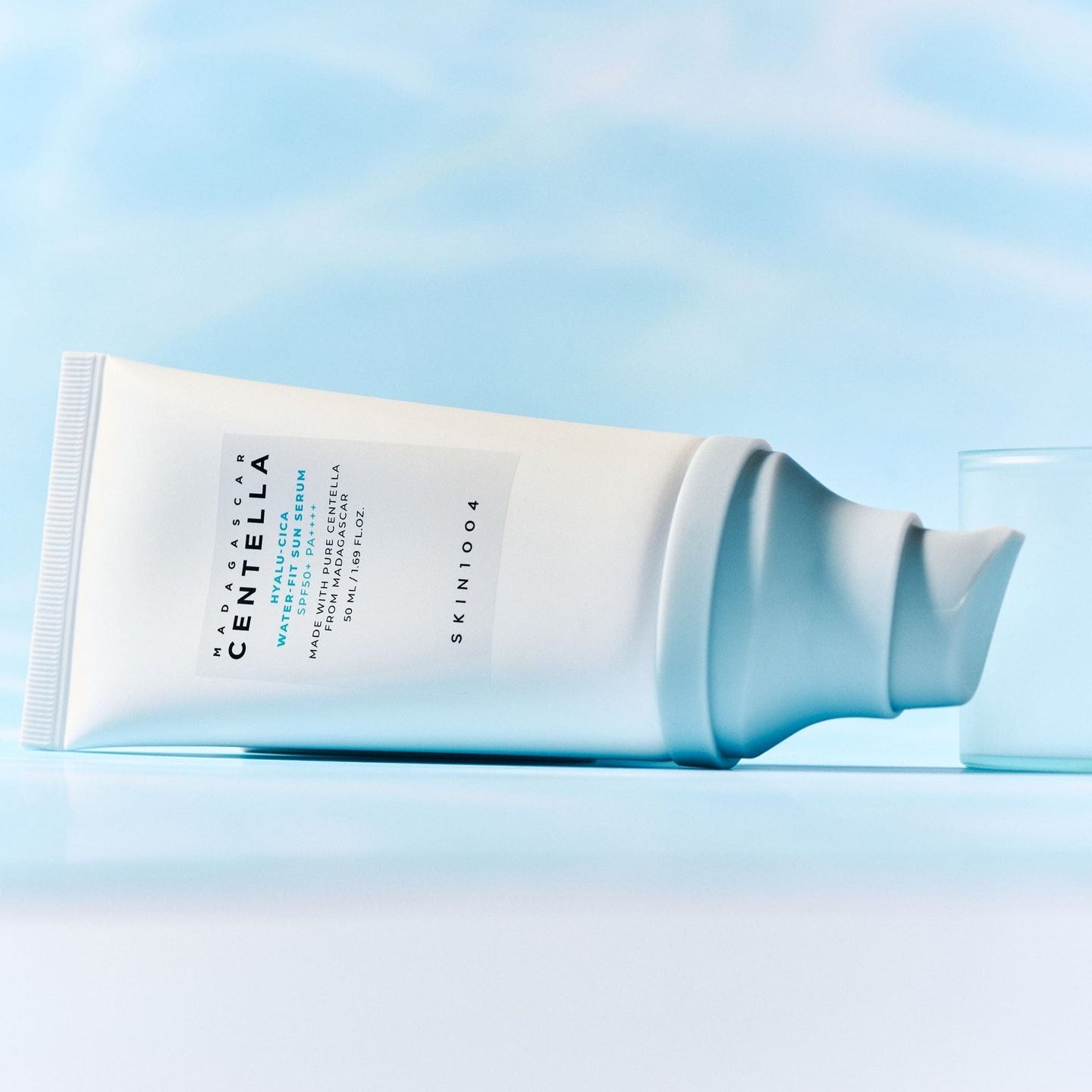 SKIN1004 Madagascar Centella Hyaluronic Acid Water-Fit Sun Serum 50ml de SKIN1004 sur fond bleu, crème solaire texturée.
