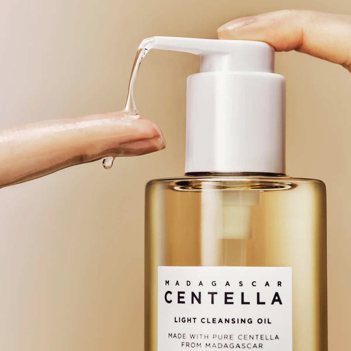 SKIN1004 Madagascar Centella Light Cleansing Oil 200ml, main verse l’huile sur peau, flacon pompe, fond salle de bain