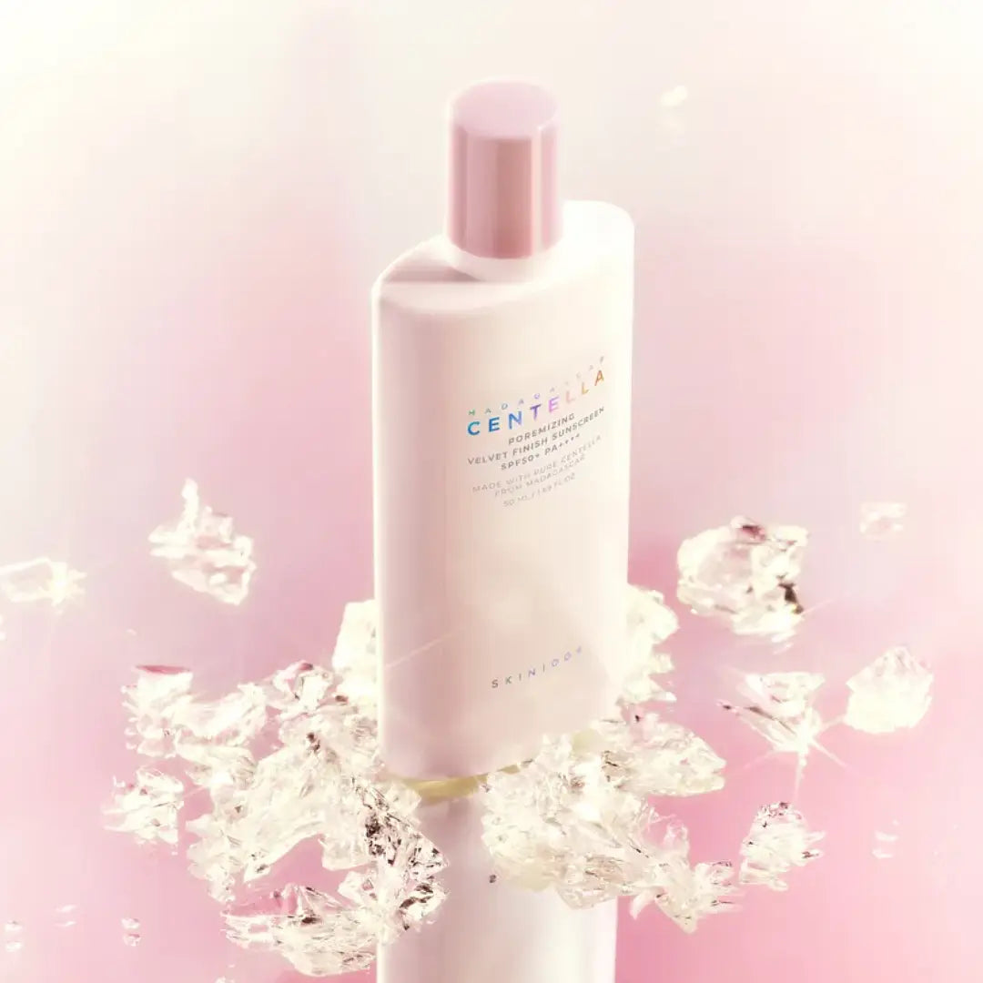 SKIN1004 Madagascar Centella Poremizing Velvet Finish Sunscreen 50ml, flacon crème visage, marque SKIN1004, fond rose avec éclaboussures.