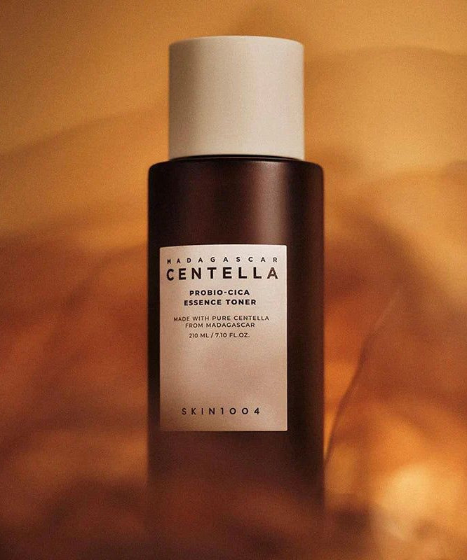 SKIN1004 Madagascar Centella Probio-cica Essence Toner 210ml, flacon noir sur fond beige chaud, présentation produit SKIN1004.
