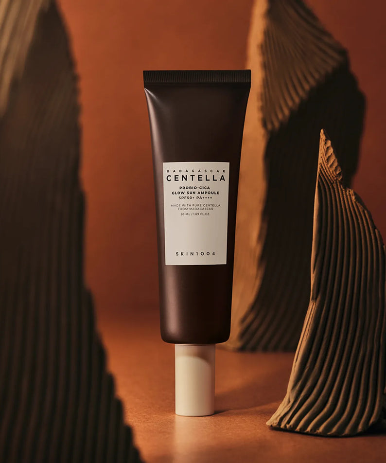 SKIN1004 Madagascar Centella Probio-cica Glow Sun Ampoule 50ml, marque SKIN1004, tube au centre sur fond chaud, esthétique skincare