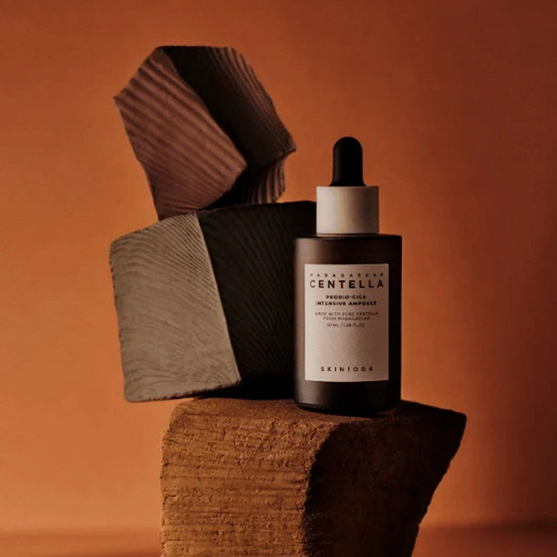 SKIN1004 Madagascar Centella Probio-cica Intensive Ampoule 50ml, SKIN1004, flacon sérum sur fond orange, ambiance spa.