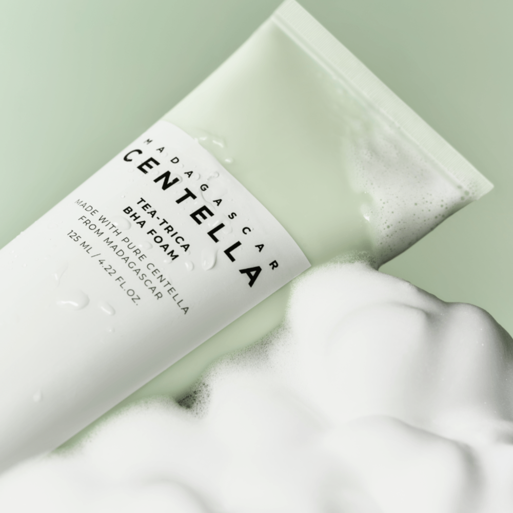 SKIN1004 Madagascar Centella Tea-trica BHA Foam 125ml, tube SKIN1004 sur mousse blanche, fond vert clair.