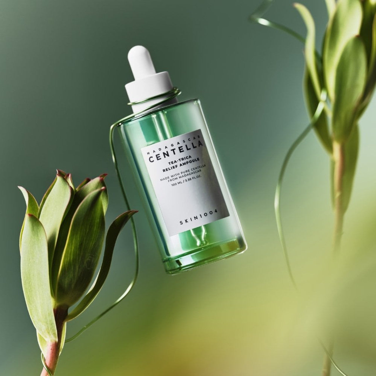SKIN1004 Madagascar Centella Tea-trica Relief Ampoule 100ml de SKIN1004, flacon vert sur fond vert avec plantes.