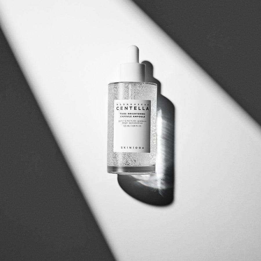 SKIN1004 Madagascar Centella Tone Brightening Capsule Ampoule 100ml, flacon sérum SKIN1004, fond noir et blanc, lumière studio.