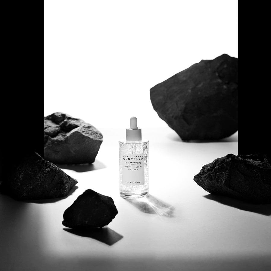 SKIN1004 Madagascar Centella Tone Brightening Capsule Ampoule 100ml de la marque SKIN1004, flacon au milieu de pierres noires sur fond blanc.