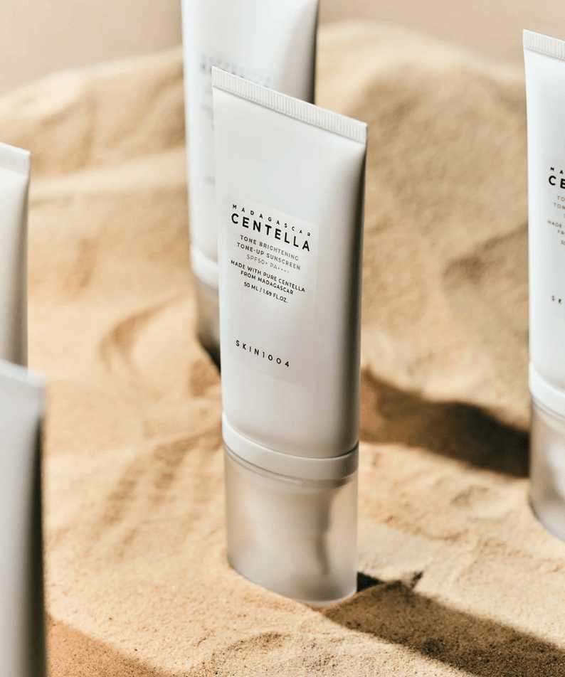 SKIN1004 Madagascar Centella Tone Brightening Tone-Up Sunscreen 50ml, tubes de crème sur fond beige, produits SKIN1004 en vitrine