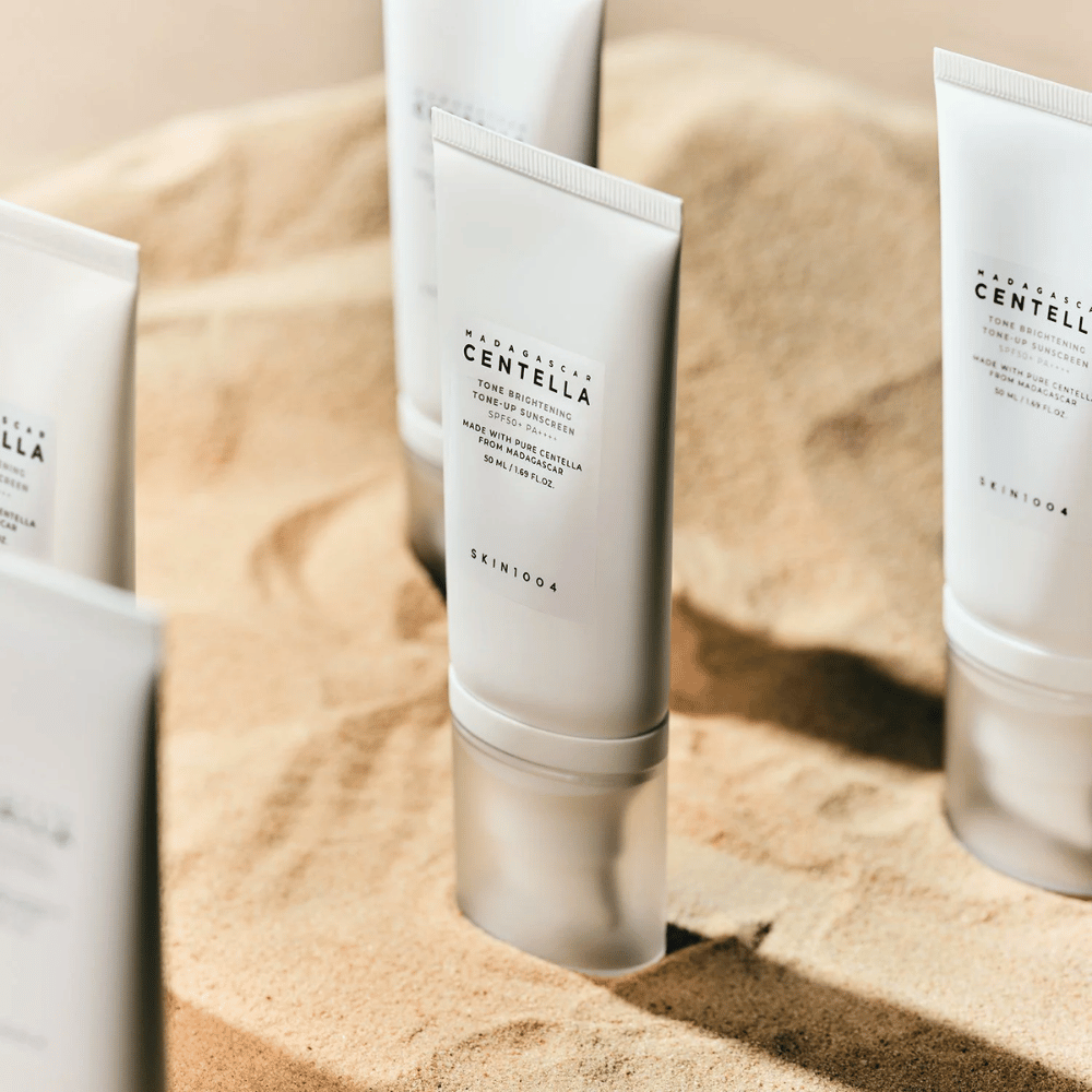 SKIN1004 Madagascar Centella Tone Brightening Tone-Up Sunscreen 50ml, tubes de crème sur fond beige, produits SKIN1004 en vitrine