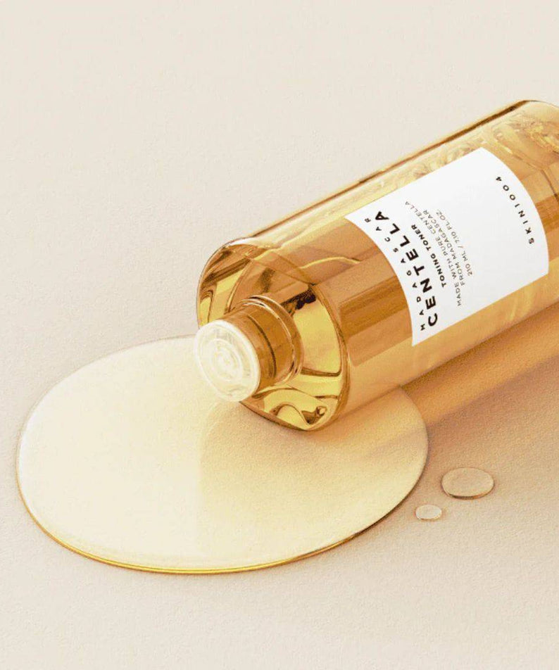 SKIN1004 Madagascar Centella Toning Toner 400ml de la marque SKIN1004, flacon ambre versant sur crème, fond clair