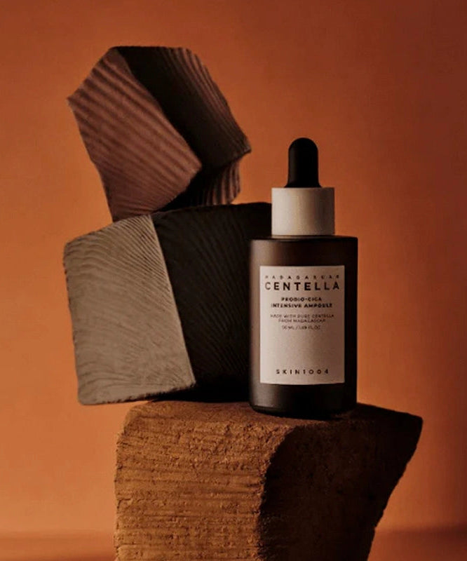 Flacon de SKIN1004 Madagascar Centella Probio-cica Intensive Ampoule 50ml devant un fond artistique, soins hydratants visage.