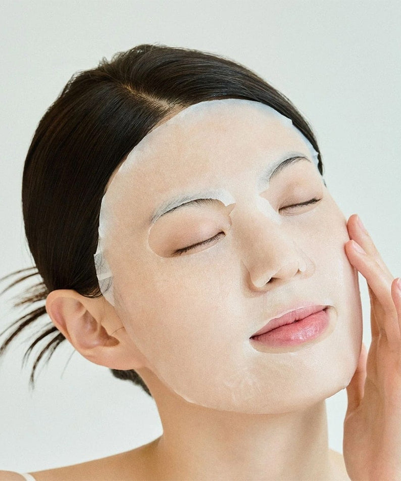 Femme portant le SKIN1004 Madagascar Centella Tone Brightening Glow Mask 25ml [5 sheets] pour éclat et tonification de la peau.