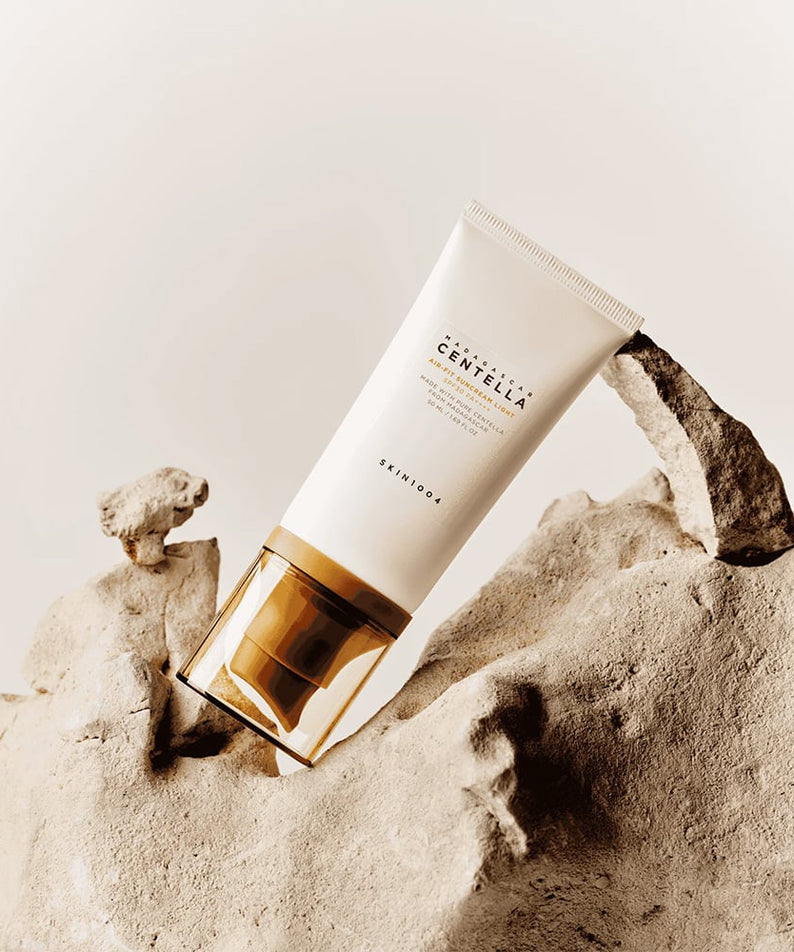 Tube de SKIN1004 Madagascar Centella Air-fit Sunscreen Light 50ml posé sur une roche, protection solaire légère pour la peau.