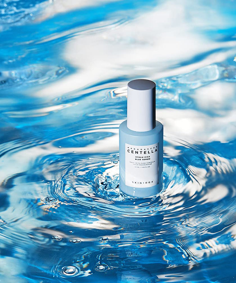 Bouteille de SKIN1004 Madagascar Centella Hyalu-Cica Blue Serum 50ml posée sur une surface d'eau bleue en mouvement.