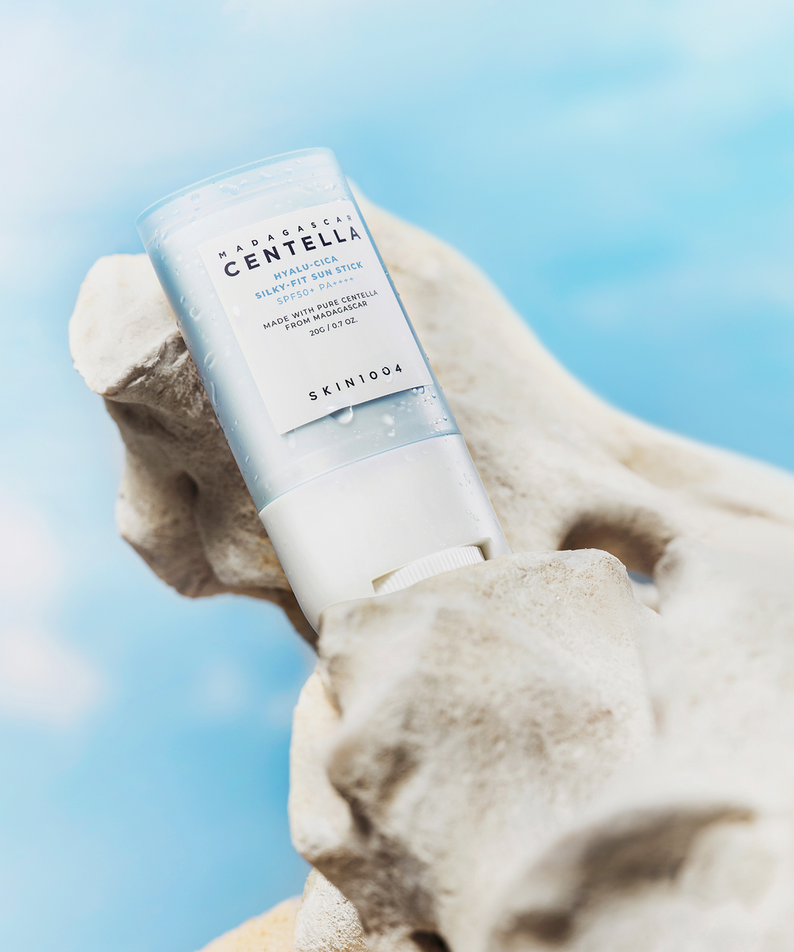 SKIN1004 Madagascar Centella Hyalu-Cica Silky Fit Sun Stick 20g posé sur une roche avec ciel bleu en arrière-plan