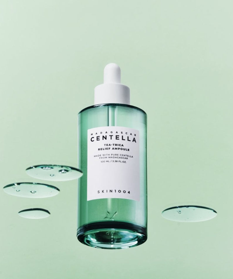 SKIN1004 Madagascar Centella Tea-trica Relief Ampoule 100ml, sérum apaisant hydratant au centella, fond vert avec gouttelettes.