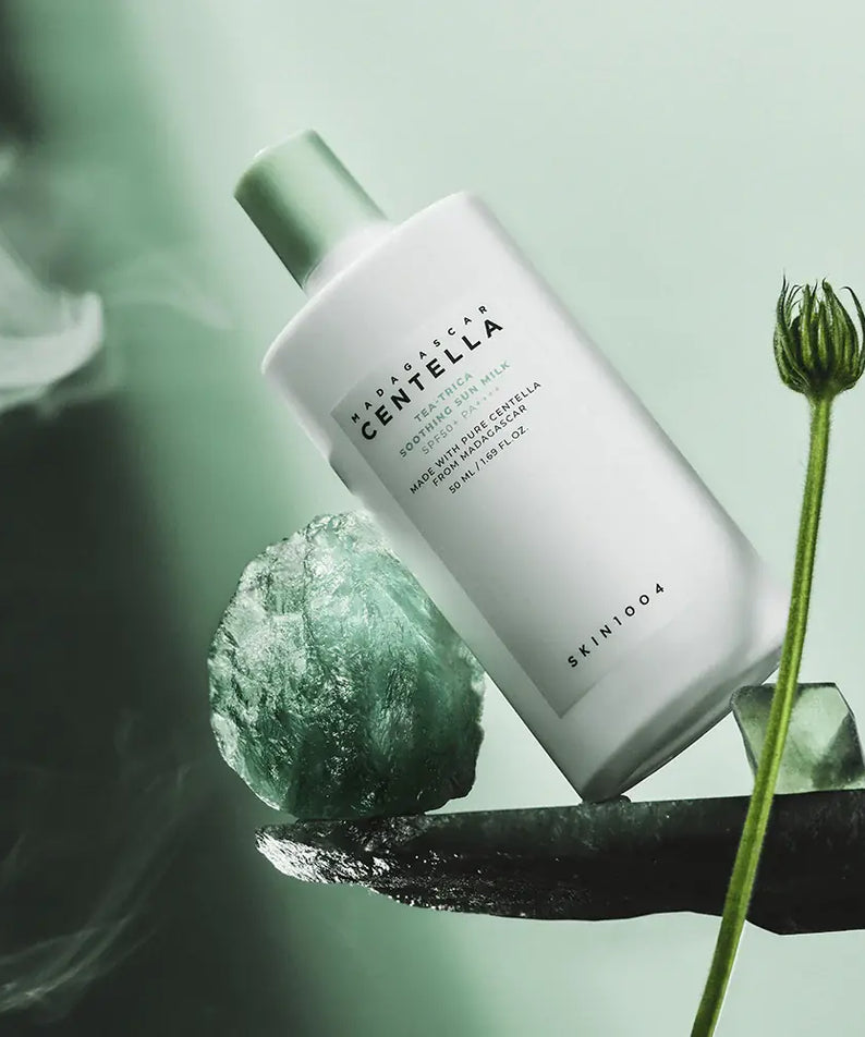 SKIN1004 Madagascar Centella Tea-trica Soothing Sun Milk 50ml sur fond vert, crème solaire apaisante en bouteille blanche.