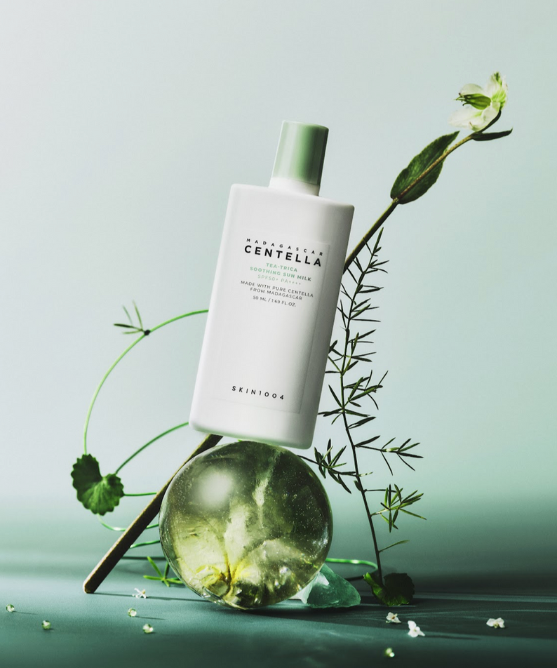 Flacon de SKIN1004 Madagascar Centella Tea-trica Soothing Sun Milk 50ml sur fond vert avec des éléments naturels.