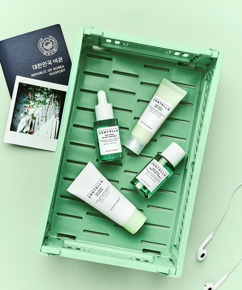 Kit de voyage SKIN1004 Madagascar Centella Teatrica dans un panier vert avec accessoires de voyage sur fond de couleur vert clair.