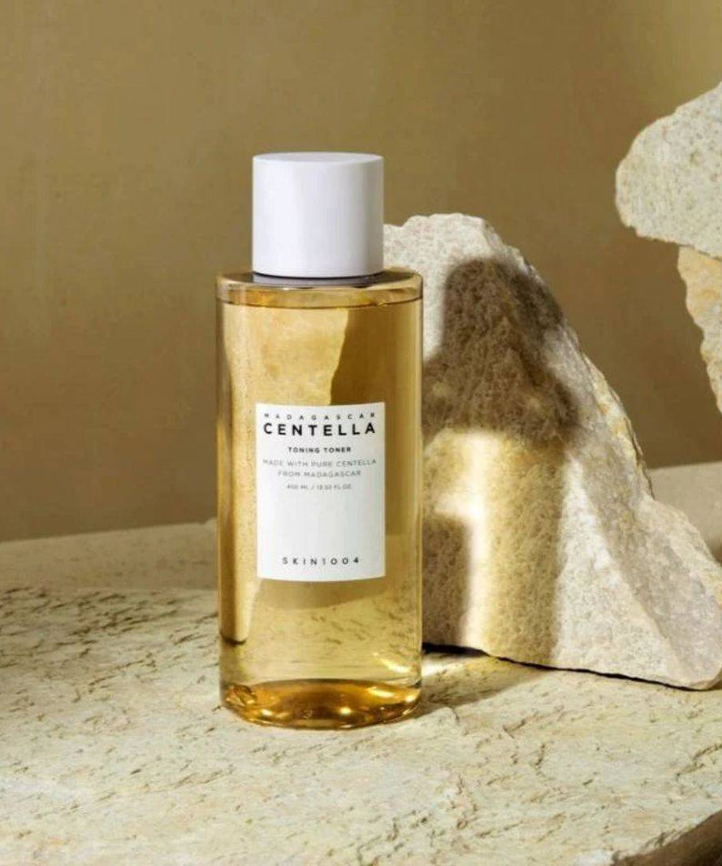 Flacon de SKIN1004 Madagascar Centella Toning Toner 400ml posé sur une roche naturelle en arrière-plan.