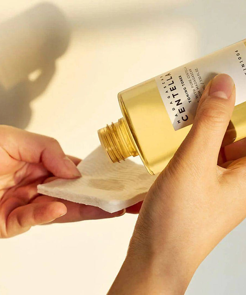 Application du SKIN1004 Madagascar Centella Toning Toner 400ml avec un coton pour une peau éclatante.