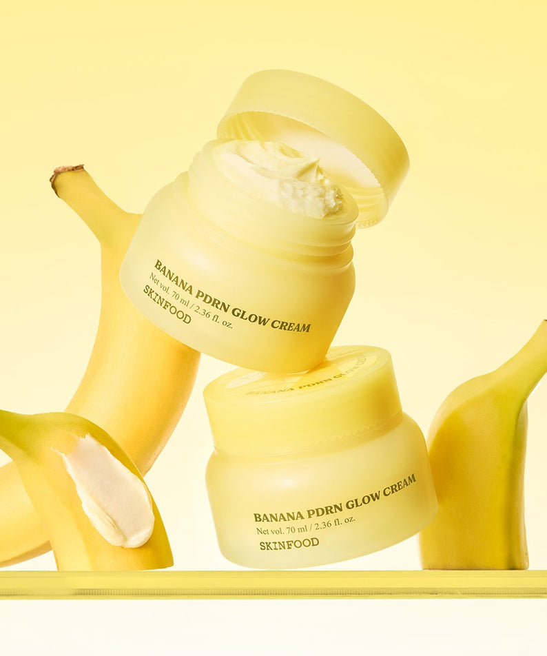 SKINFOOD Banana PDRN Glow Cream 70ml de marque SKINFOOD, crème lumineuse avec bananes, fond jaune en studio.