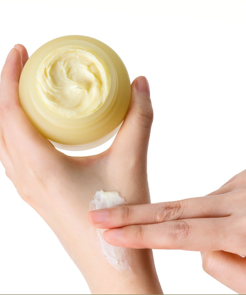 SKINFOOD Banana PDRN Glow Cream 70ml, pot de crème cosmétique jaune, texture sur les mains, studio blanc.