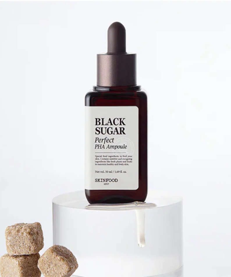 SKINFOOD Black Sugar Perfect PHA Ampoule 50ml, sérum marque SKINFOOD présenté sur socle blanc avec pièces en arrière-plan