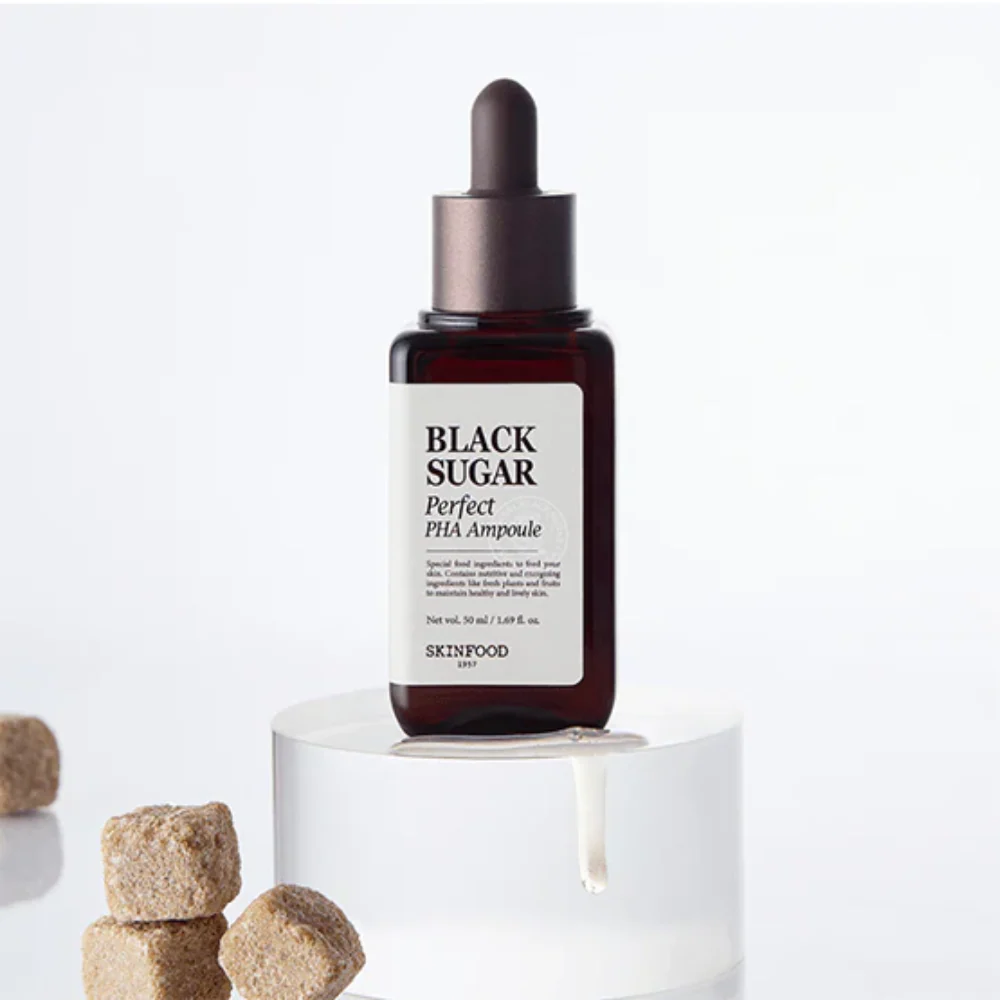 SKINFOOD Black Sugar Perfect PHA Ampoule 50ml, sérum marque SKINFOOD présenté sur socle blanc avec pièces en arrière-plan