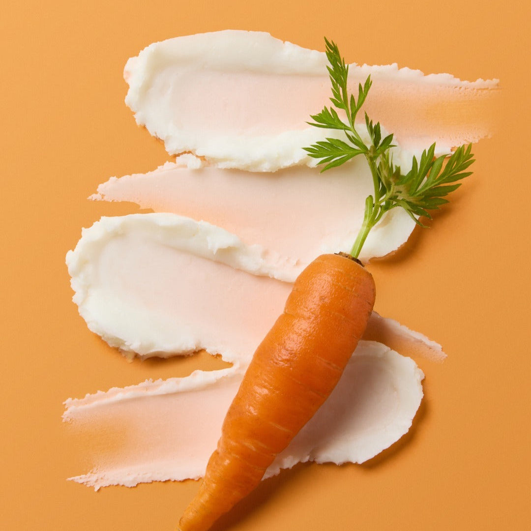 SKINFOOD Carrot Airy Soft Sun Stick 18.5g, stick solaire sur décor carotte et feuilles, fond orange, lifestyle.
