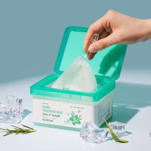 SKINFOOD [NEW] Basil Tea Tree Cynic Daily Mask 30 Sheets : masque en tissu, main ouvre la boîte, décor frais turquoise, plantes.