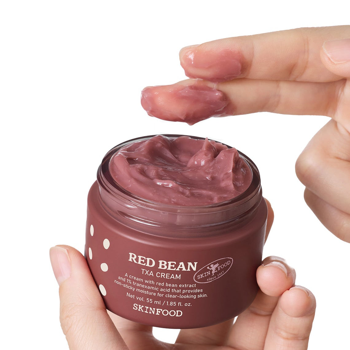 SKINFOOD Red Bean Tranexamic Acid Cream 55ml en pot brun, texture crème rose, main tenant le produit sur fond blanc.
