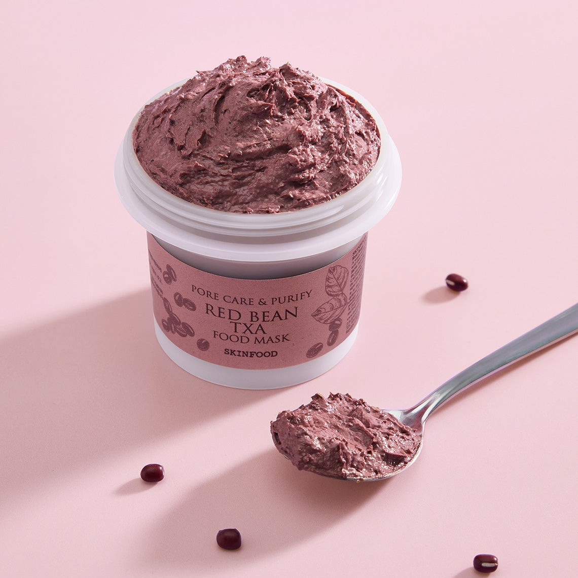 Décris l'image en français : pot SKINFOOD Red Bean Tranexamic Acid Food Mask 120g, texture crème violette sur fond rose.