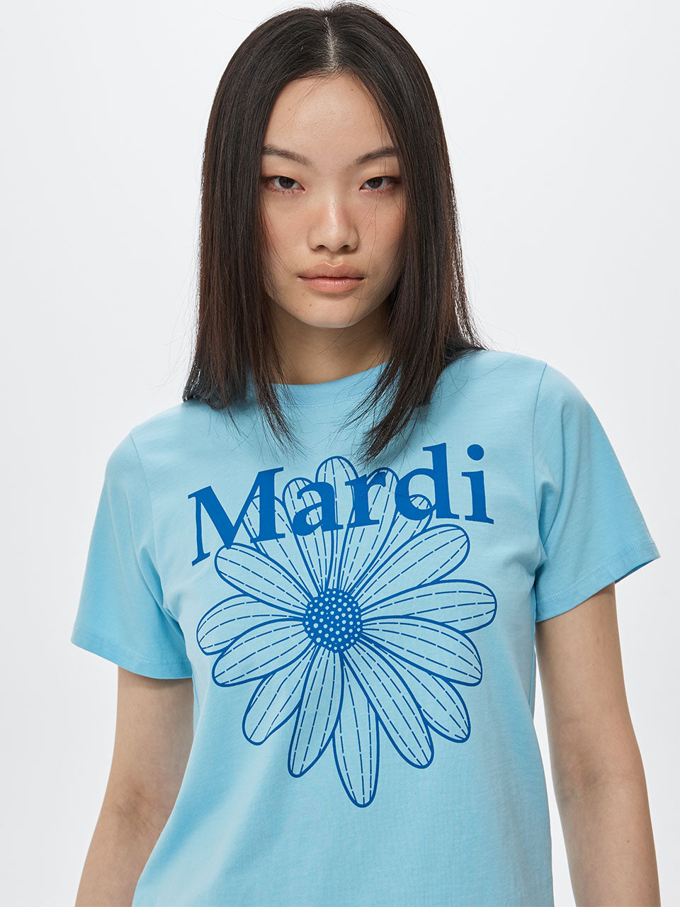 SLIM TSHIRT FLOWERMARDI_SKY BLUE Mardi Mercredi, t-shirt sky bleu slim avec fleur Mardi, modèle posant sur fond clair.