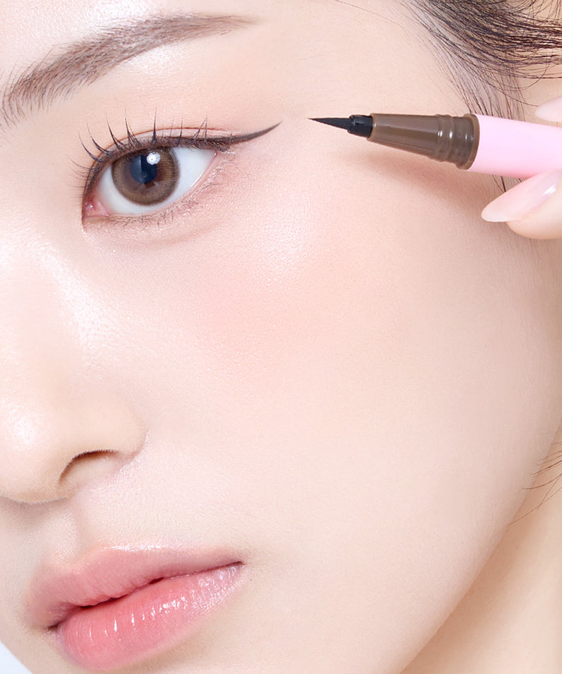 SO NATURAL Super Fix Slim Pen Eyeliner : application sur l’œil, main tenant le stylo noir, gros plan maquillage naturel.