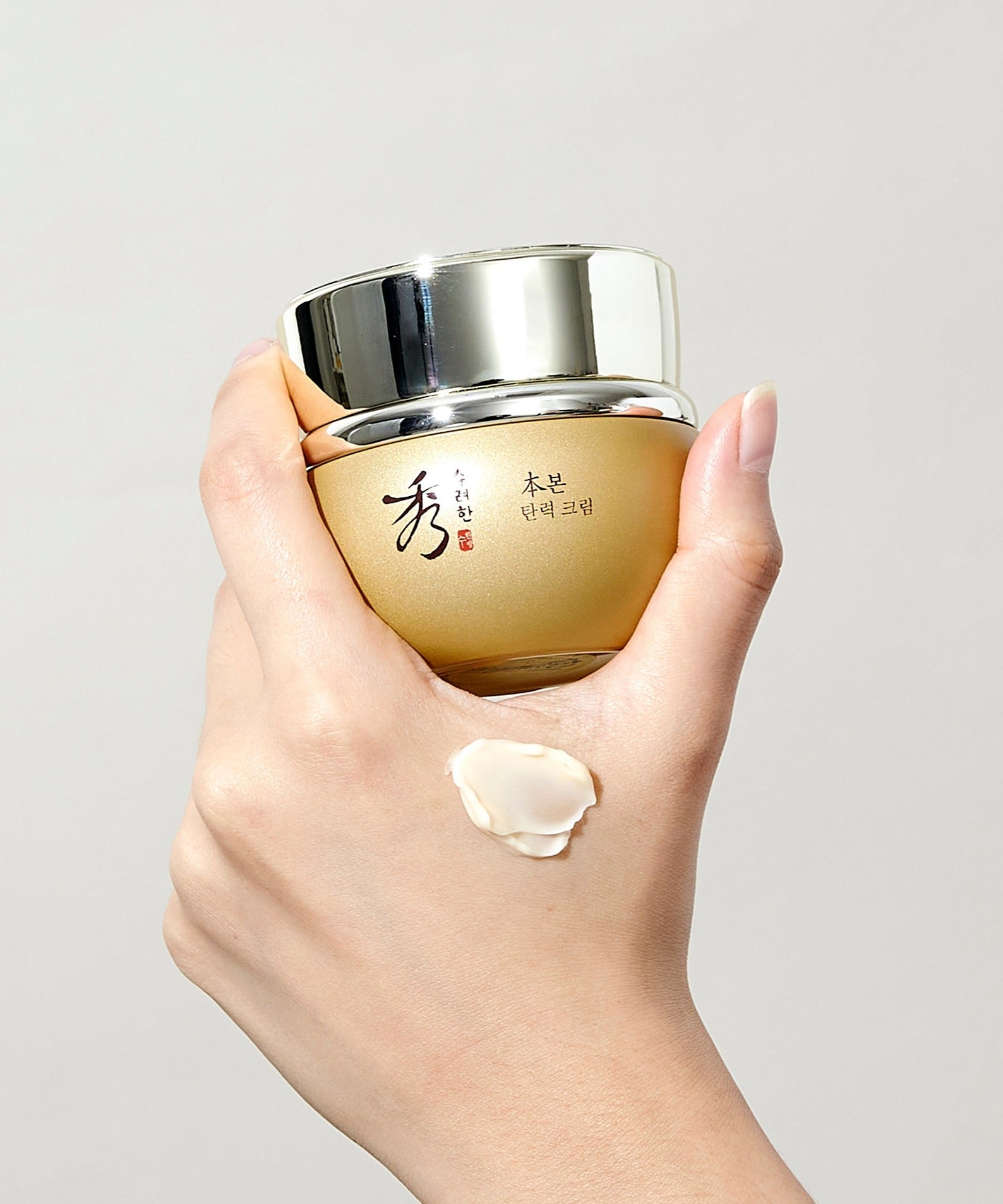 SOORYEHAN Bon Elasticity Cream 75ml : crème hydratante en pot doré, main appliquant une texture, fond clair.