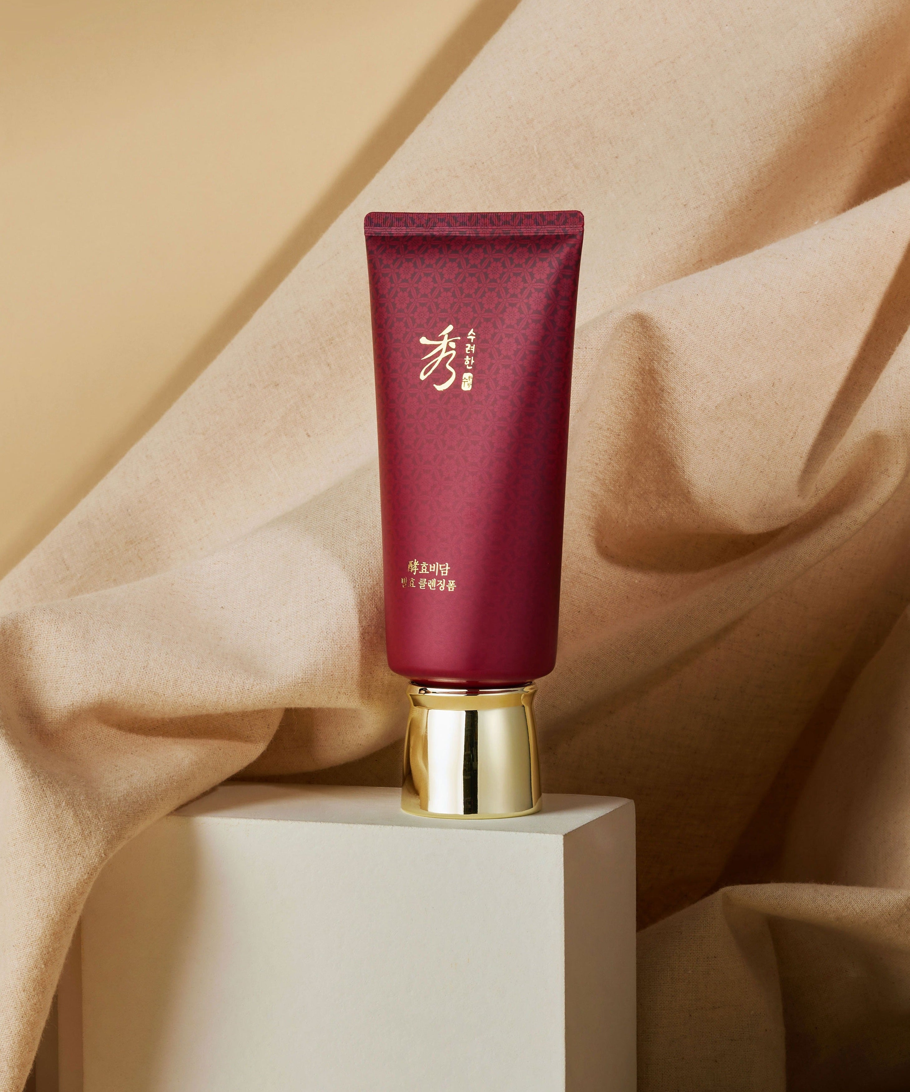 SOORYEHAN Hyobidam Fermented Cleansing Foam 160ml sur podium, flacon rouge bordeaux, tissu beige en arrière-plan.