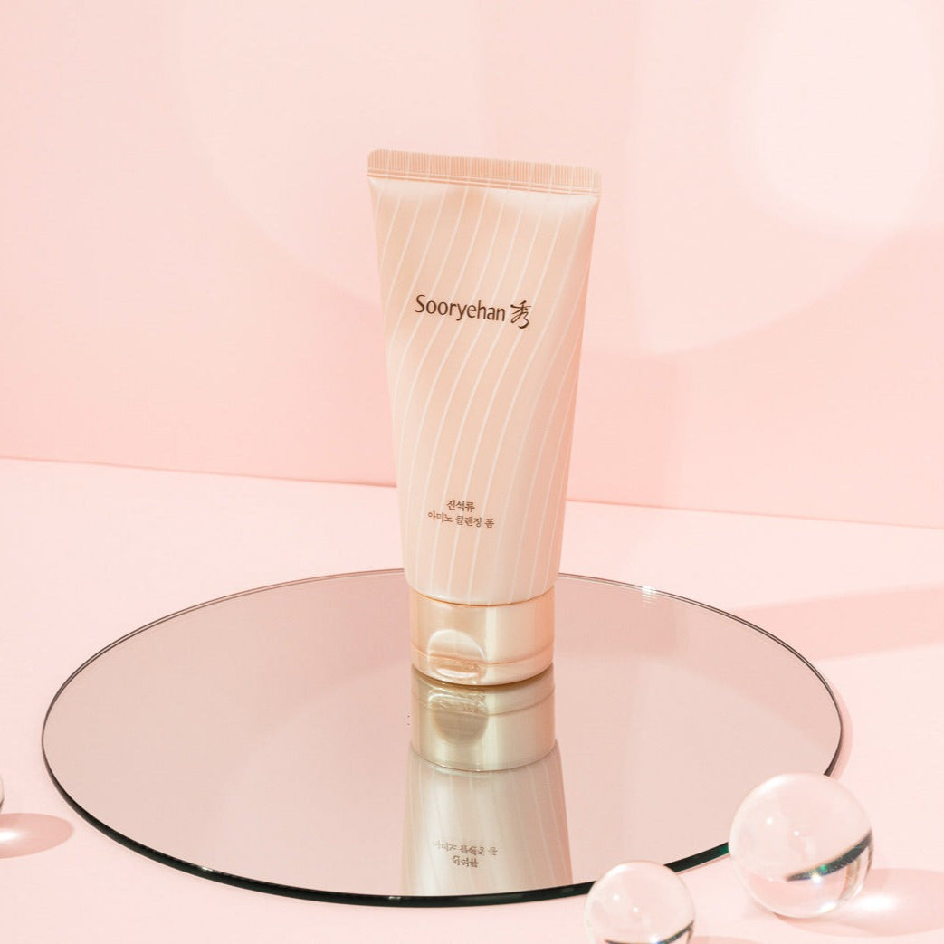 SOORYEHAN Jinseokryu Amino Cleansing Foam 160ml de SOORYEHAN, tube blanc sur fond rose pastel avec reflets cosmétiques