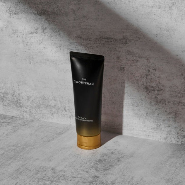 SOORYEHAN The Black Amino Cleansing Foam 150ml : tube noir SOORYEHAN sur fond marbre gris, éclairage studio.