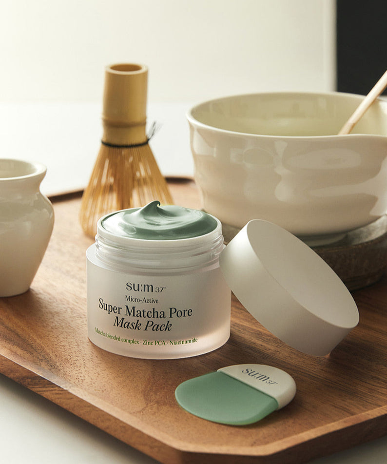 SU:M37 Microactive Super Matcha Pore Mask 100ml en pot ouvert sur un plateau, avec accessoires pour le soin du visage en arrière-plan.